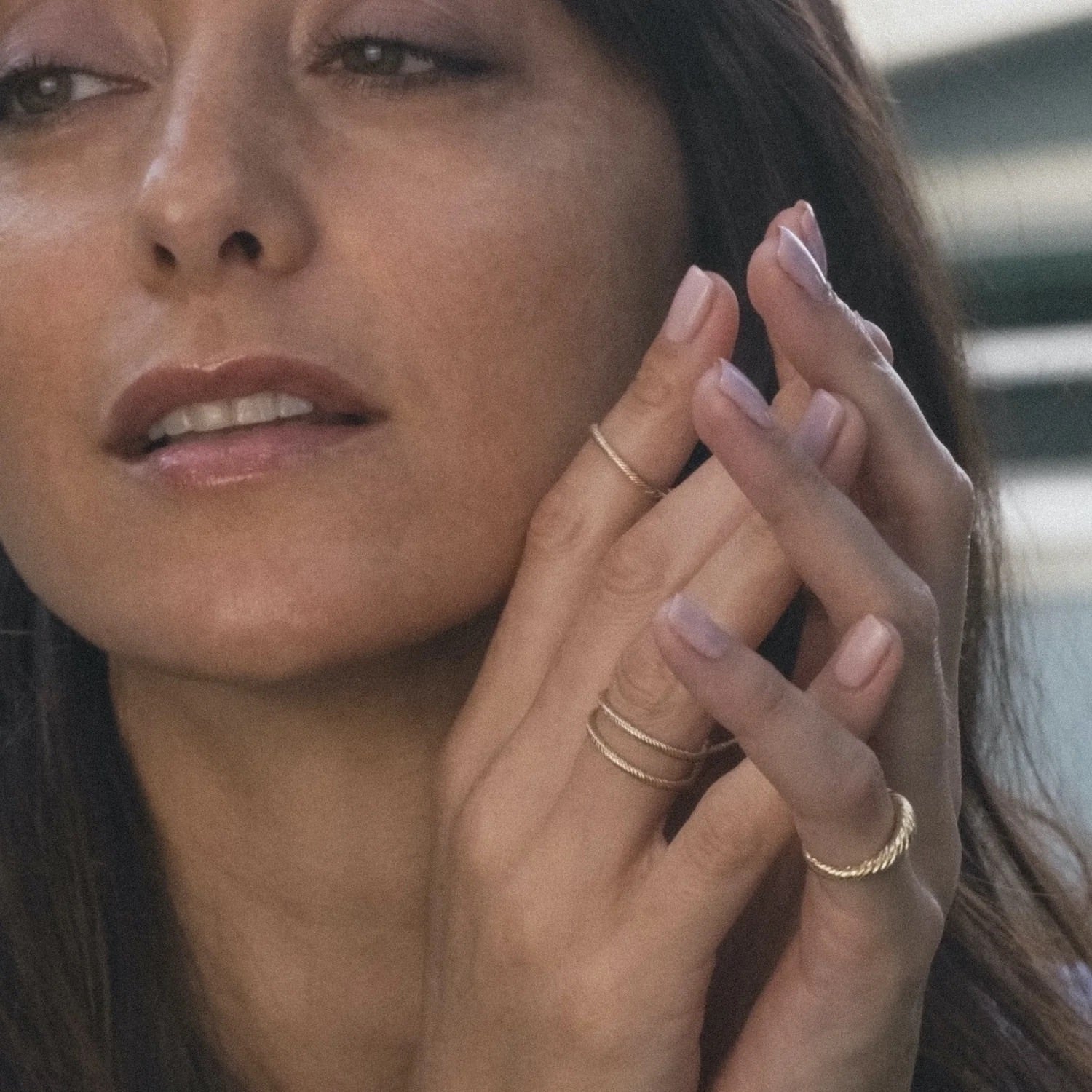 Textured gold rings worn on model, showcasing intricate twisted details and minimalist design.