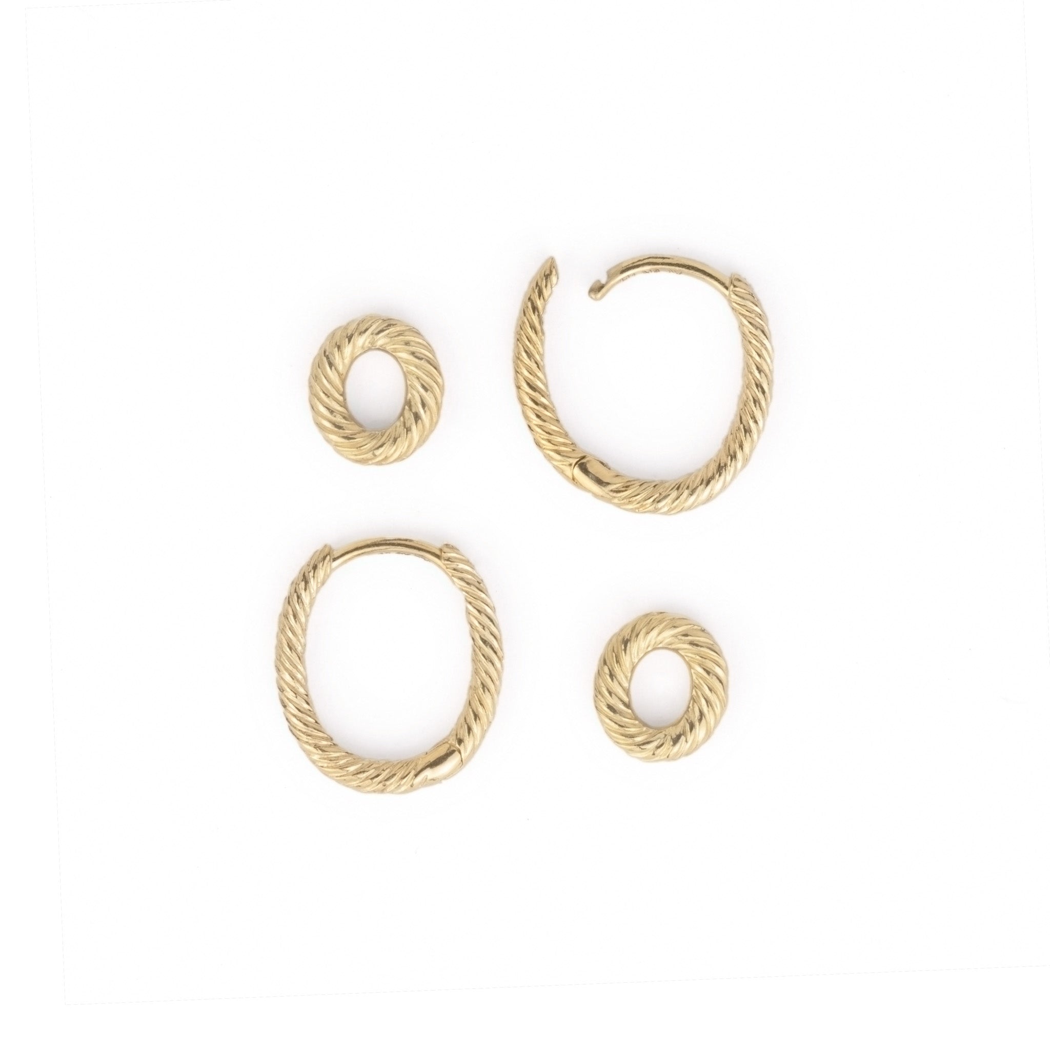 Flatlay of solid gold hoop earrings and link charms, showing secure hinged-snap closure and twisted texture.