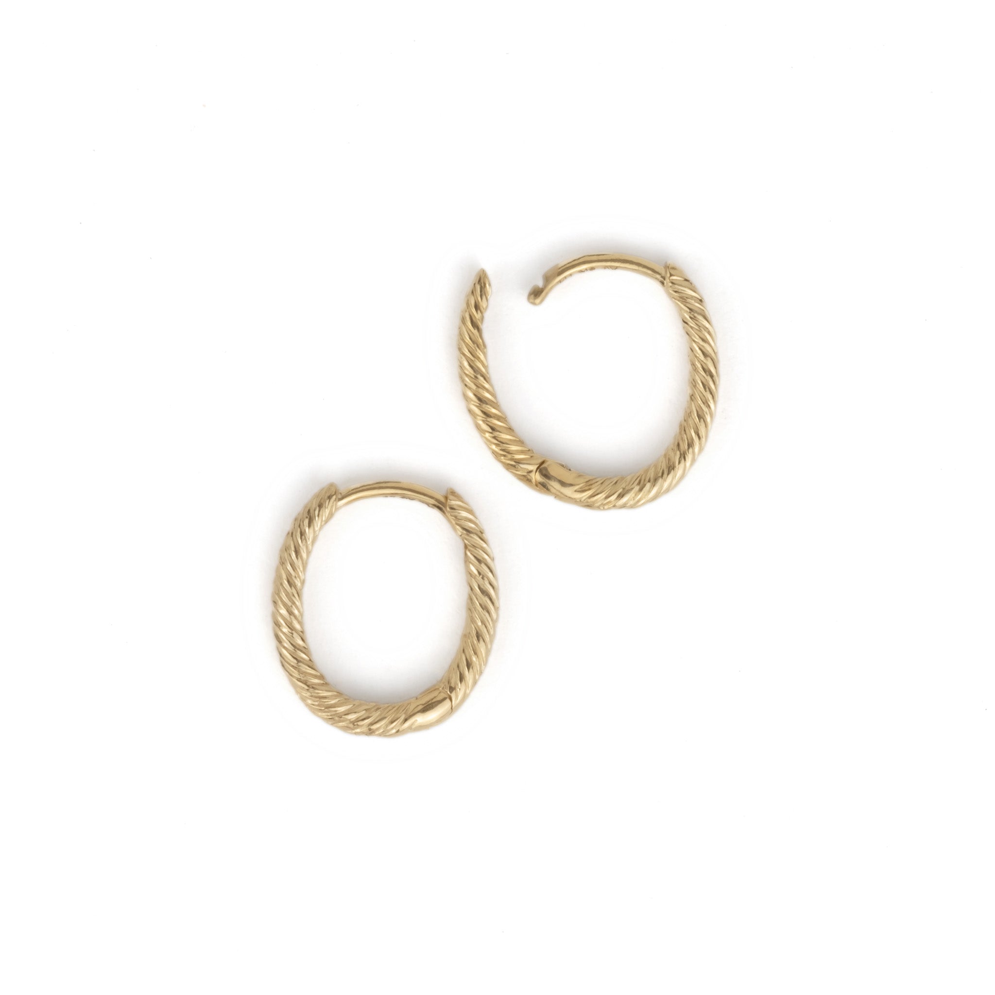 Flatlay of solid gold hoop earrings showing oval shape, twisted texture, and minimalist design on white background.