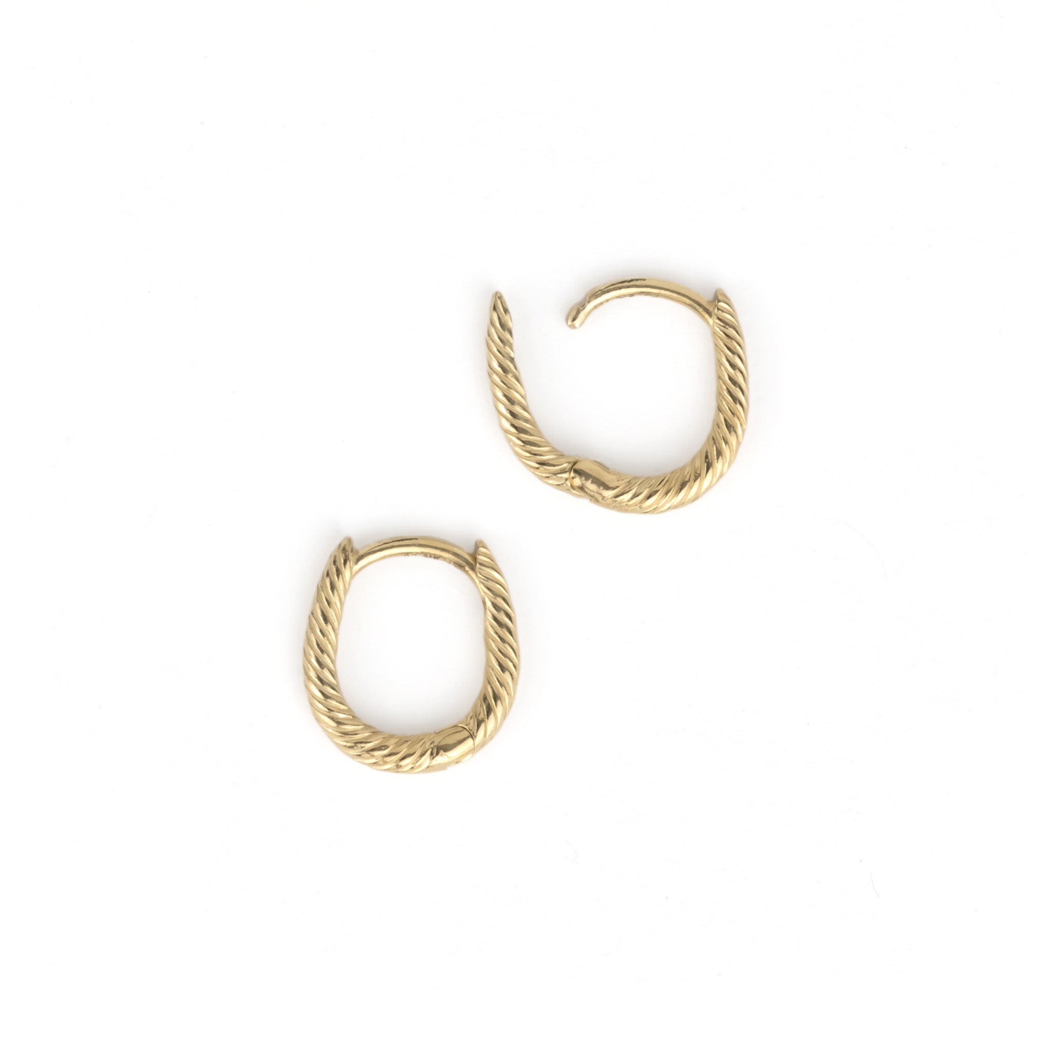 Flatlay of solid gold oval huggie hoop earrings with twisted texture, showing open hinged-snap closure on white background.