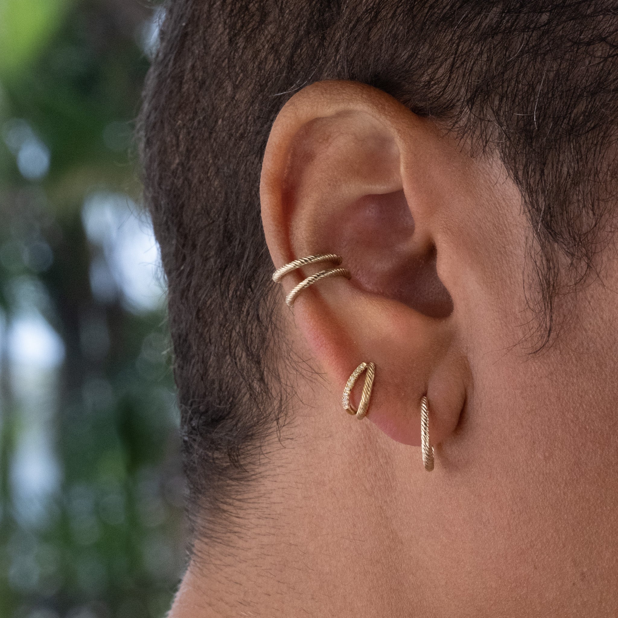 Solid gold hoop styled with diamond double hoop and ear cuffs, all with twisted texture, worn in minimalist earring stack.
