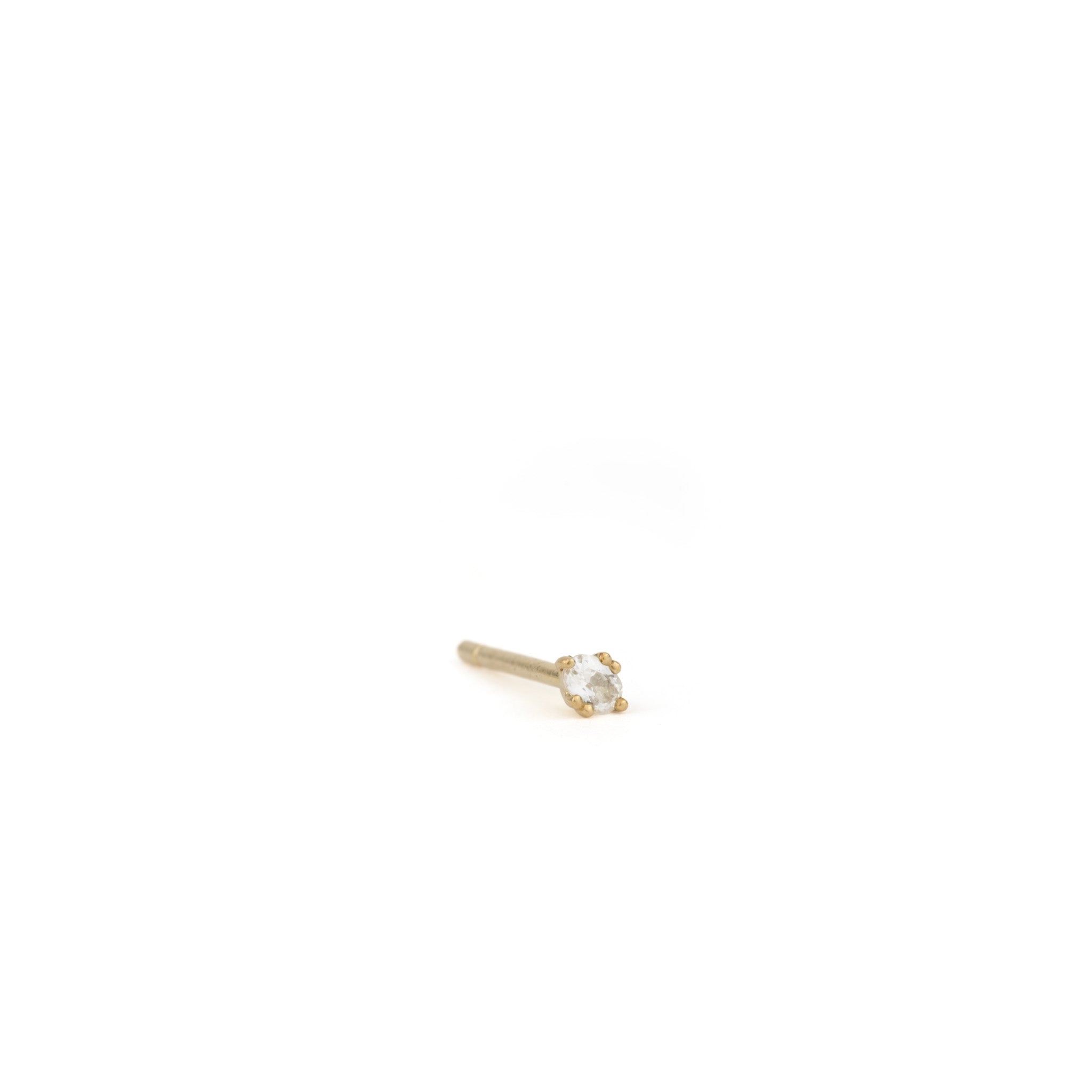 Solid gold oval stud earring in white sapphire with minimalist design and unique prong setting, angled on white background.