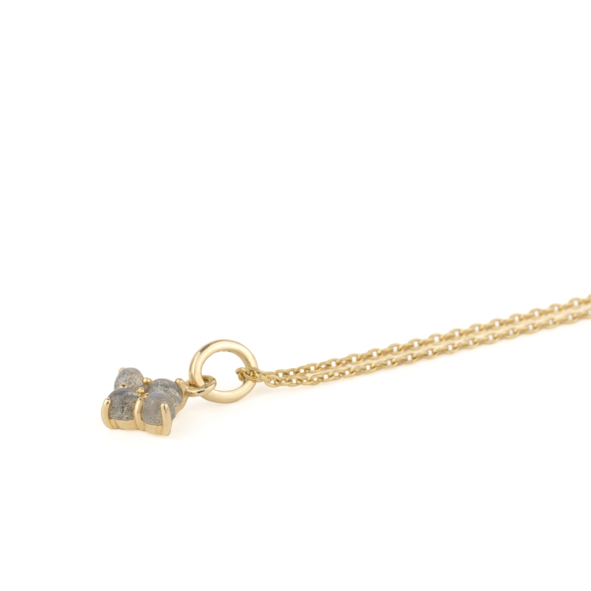 Solid gold charm pendant with cabochon labradorites, in minimalist design, on cable chain, laying angled on white background.