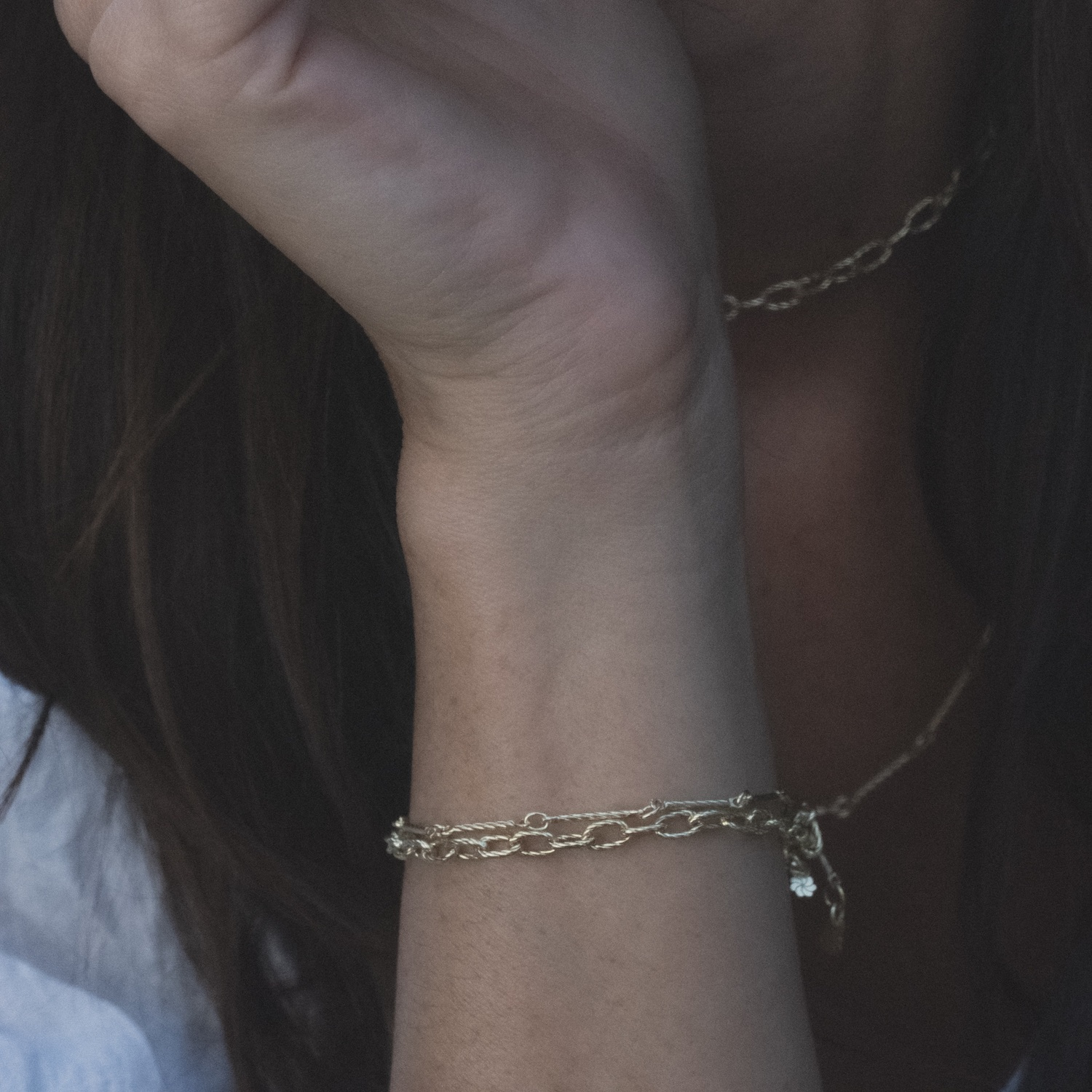Model's arm wearing Aiden Jae's yellow gold bracelets with twisted texture.