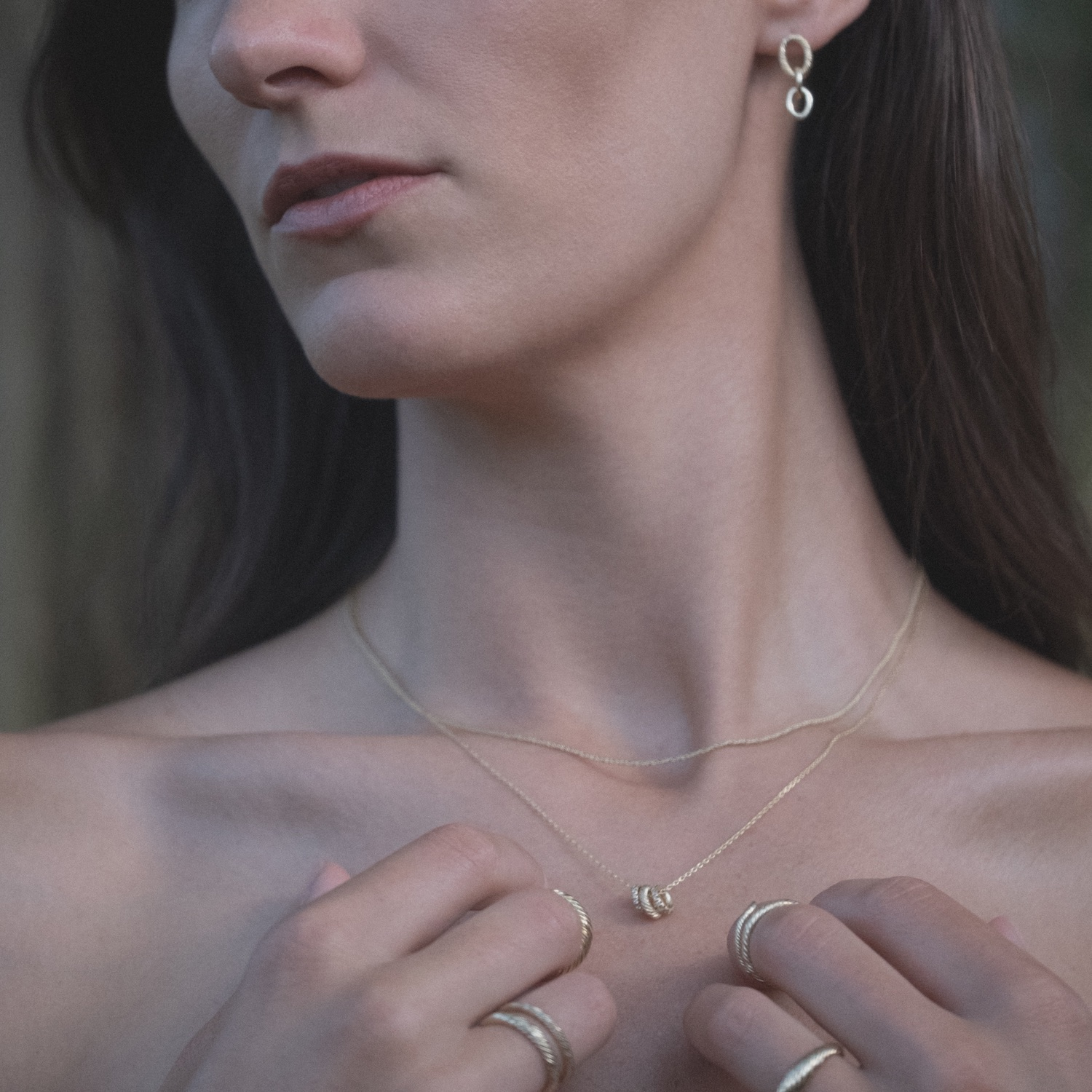 Model wearing Aiden Jae's textured yellow gold earrings, rings, and necklaces.