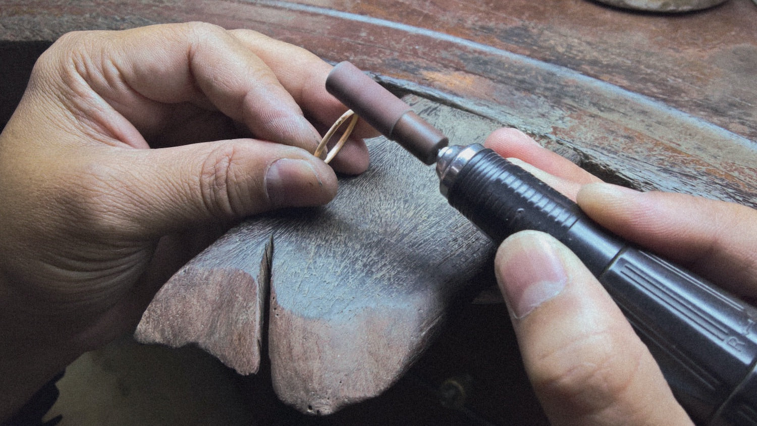 Jeweler working on yellow gold ring at jewelry bench.