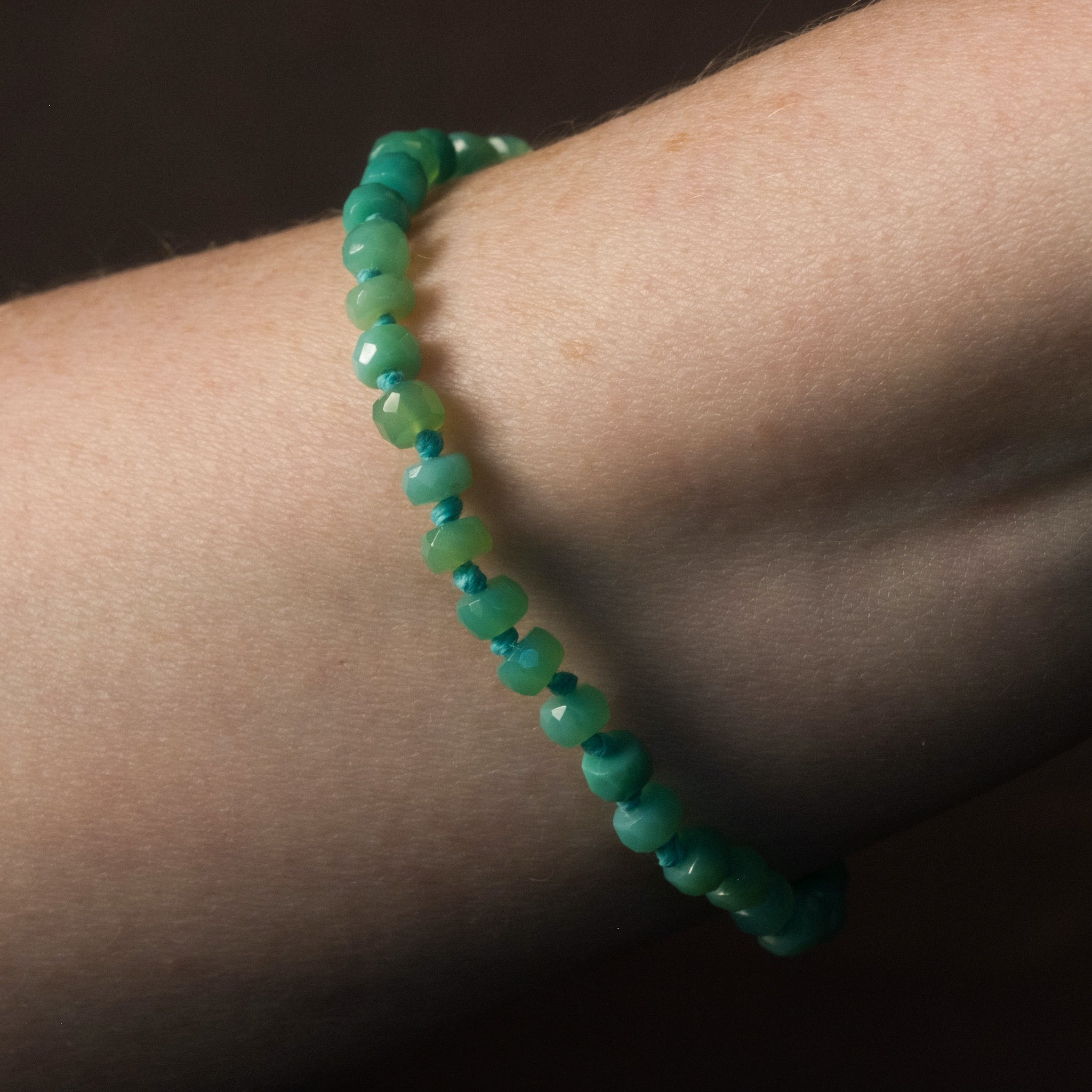 Knotted bead bracelet in faceted chrysoprase with seafoam blue-green hemp, worn on wrist.