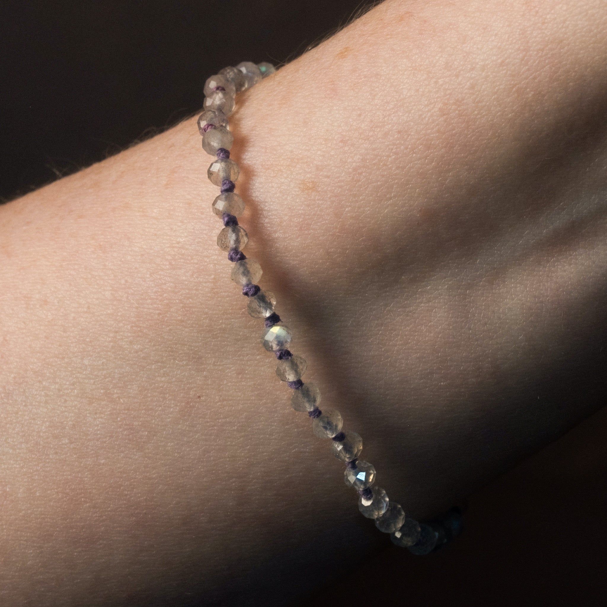 Knotted bead bracelet with faceted labradorite and ombré hemp in blue, grey, and violet, worn on wrist.