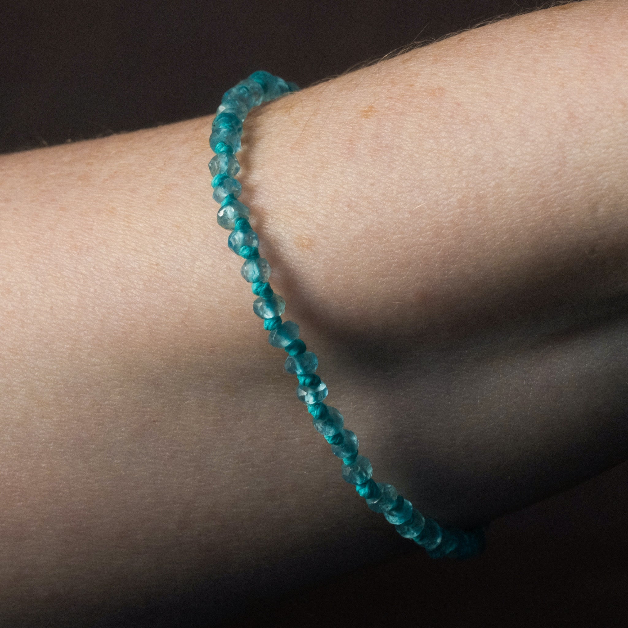 Knotted bead bracelet in faceted apatite with seafoam blue-green hemp, worn on wrist.