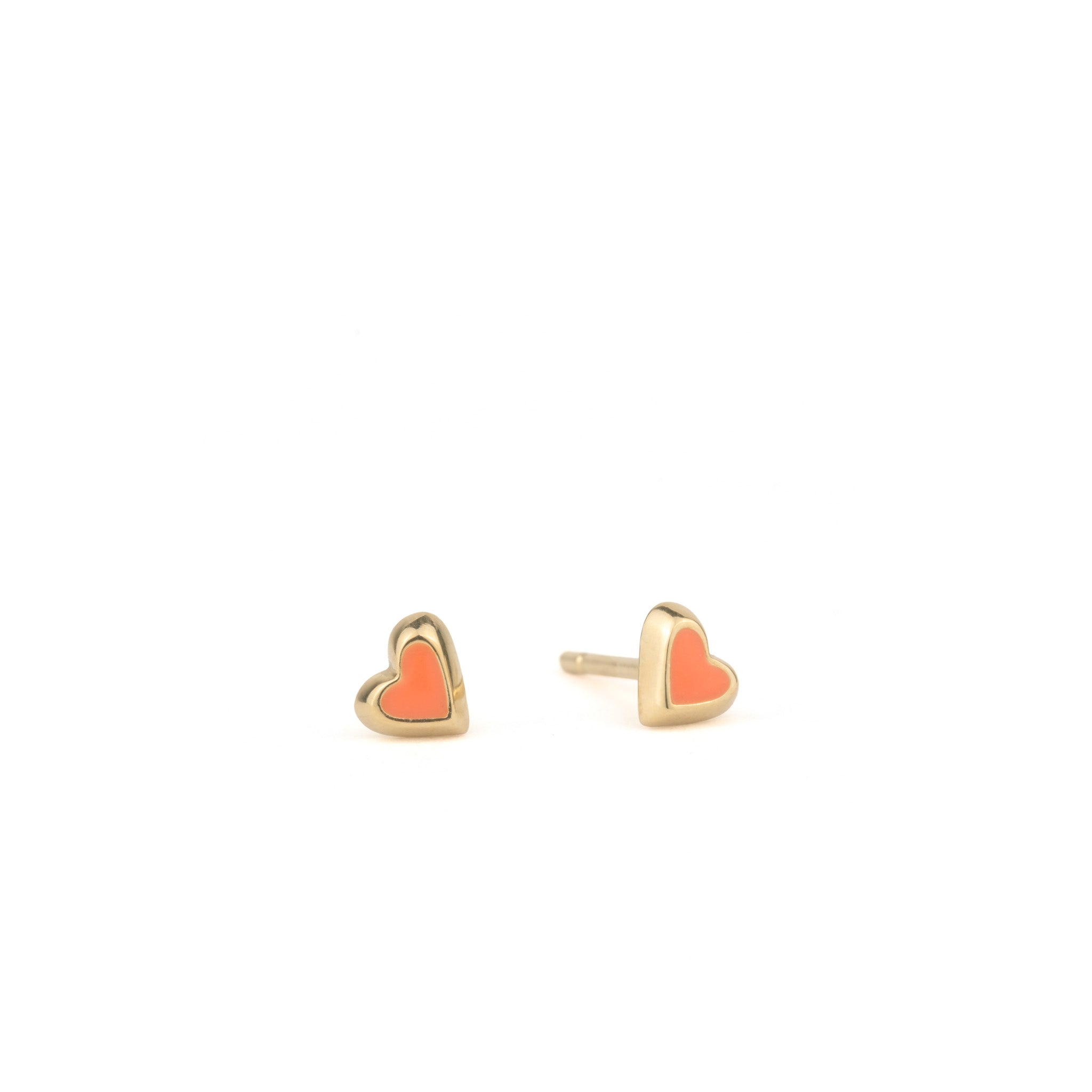 Solid gold tiny heart stud earrings with coral enamel, in a minimalist asymmetrical design, displayed on white background.