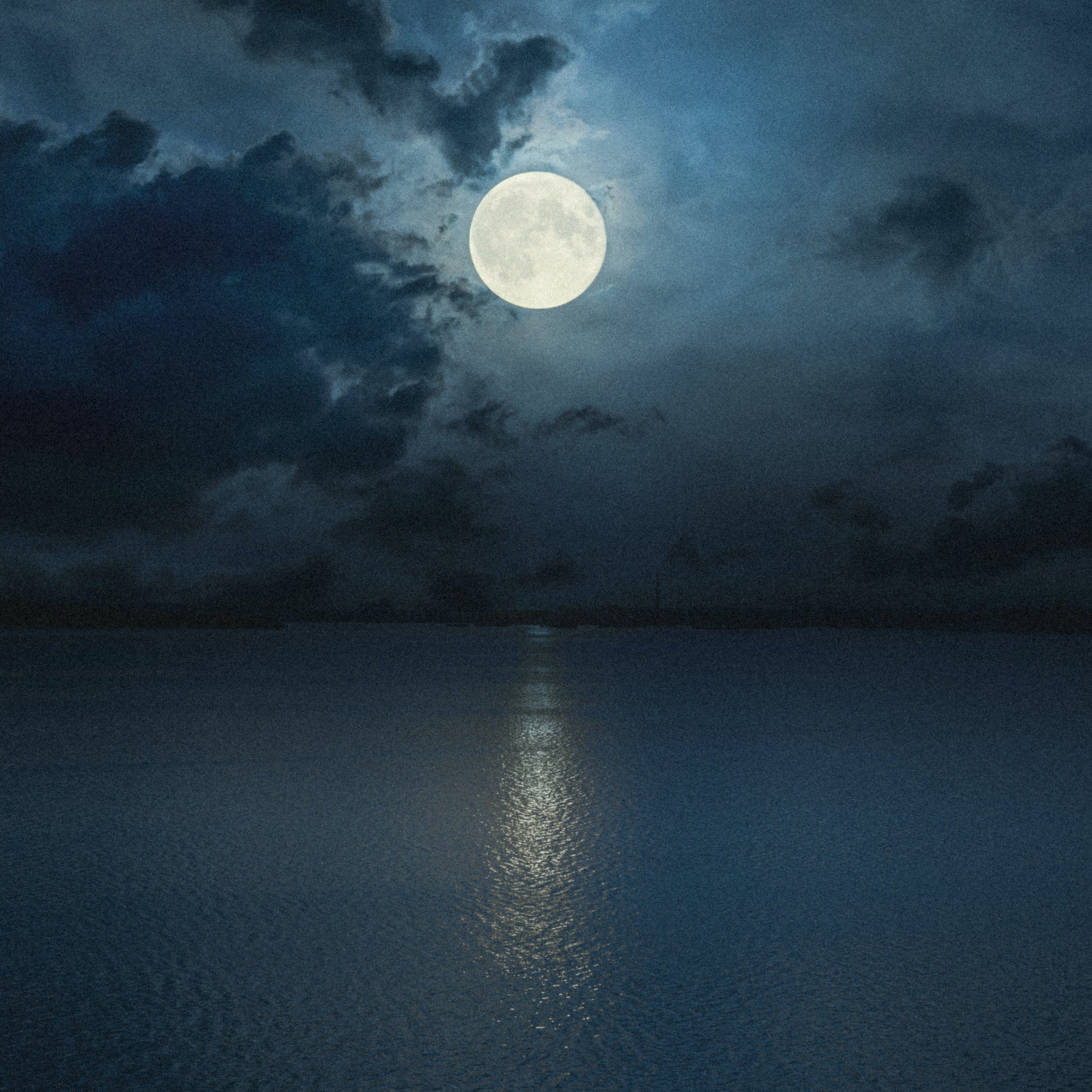 Large moon casting a shimmering beam over the blue ocean, natural color inspiration.