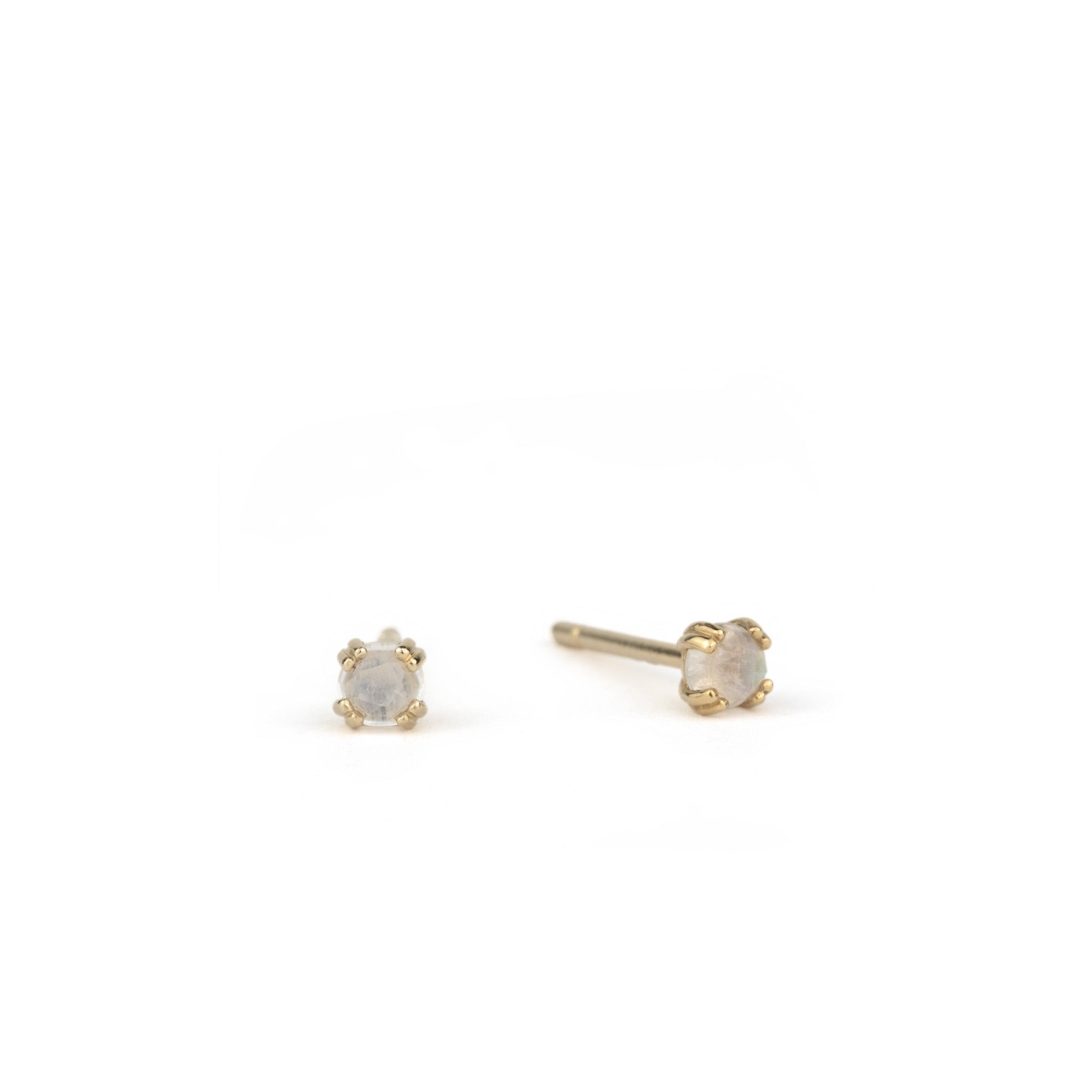 Small solid gold stud earrings with rose cut faceted rainbow moonstone in a doubled prong setting, on white background.