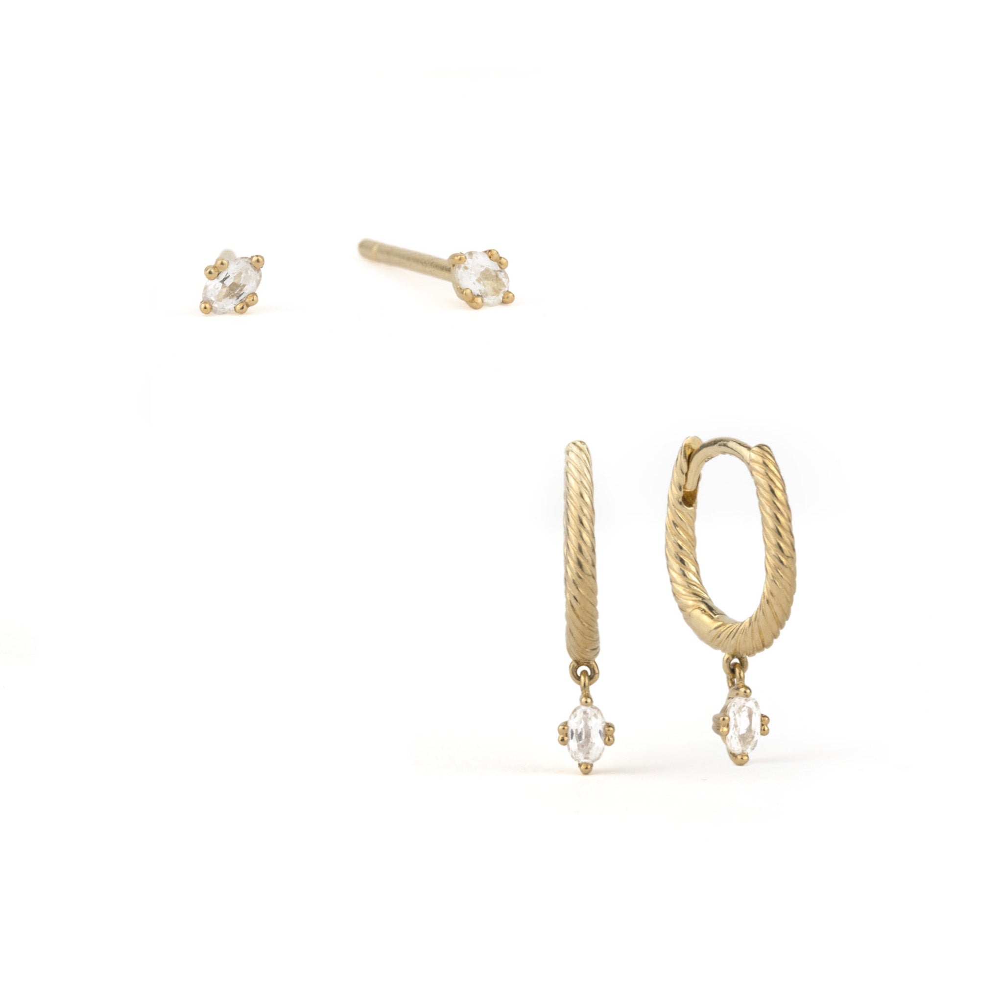 Tiny solid gold oval stud earrings and textured huggies with dangling drops in white sapphire, stacked on white background.