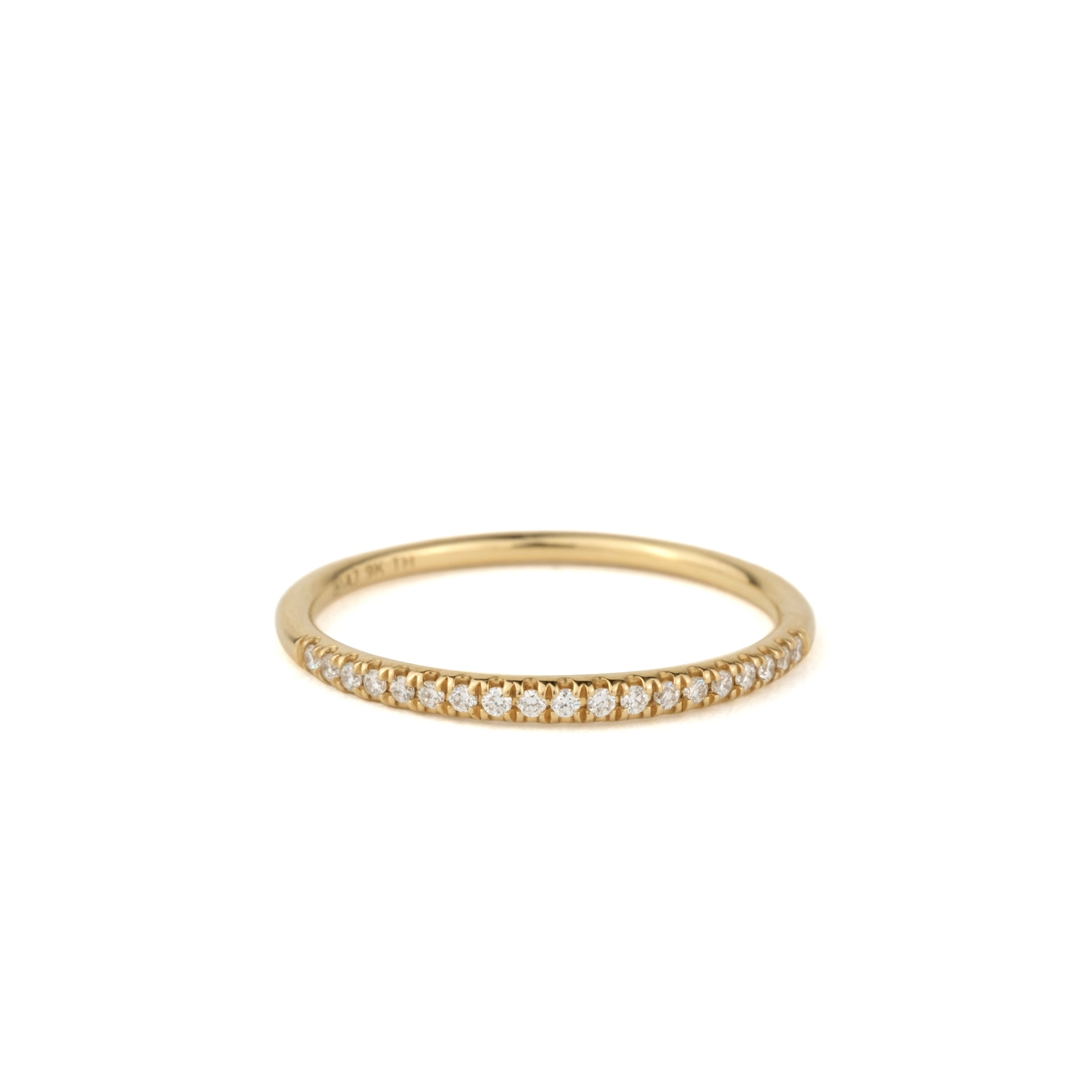 Thin solid gold stackable band ring with split-prong set brilliant diamonds, in a minimalist design, on white background.