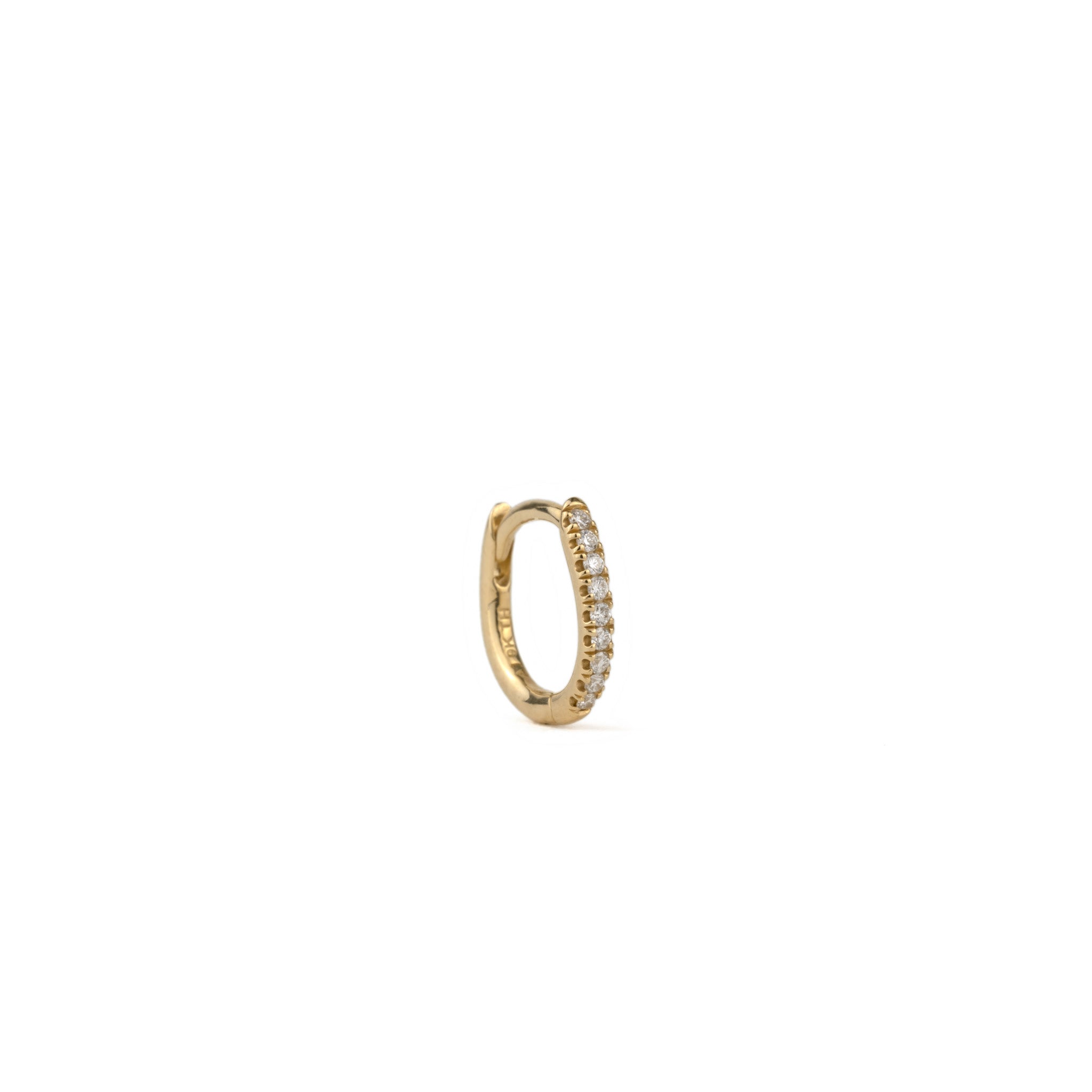 Solid gold huggie hoop earring with split-prong set brilliant diamonds, in a minimalist design, angled on white background.