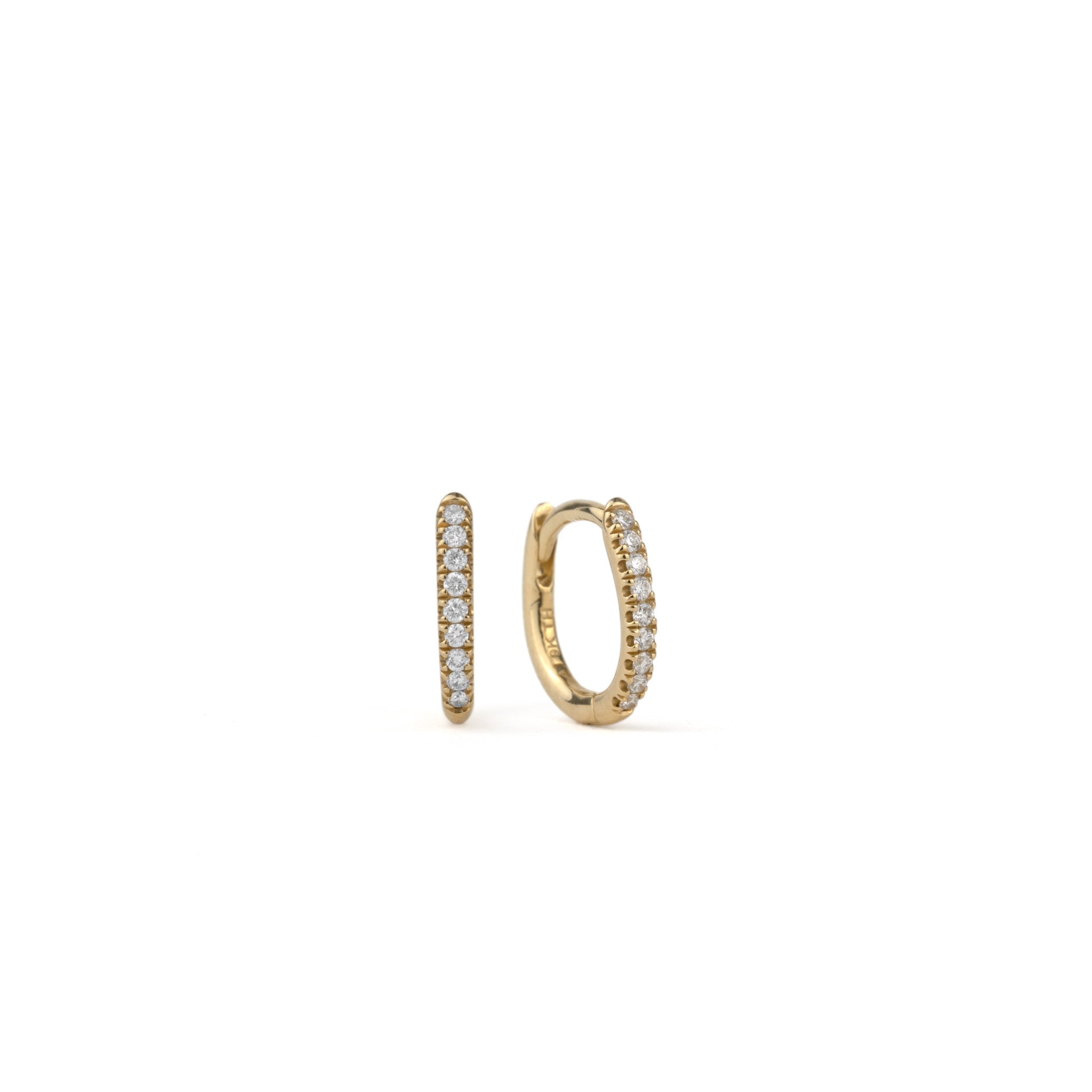 Solid gold huggie hoop earrings with split-prong set brilliant white diamonds, in a minimalist design, on white background.