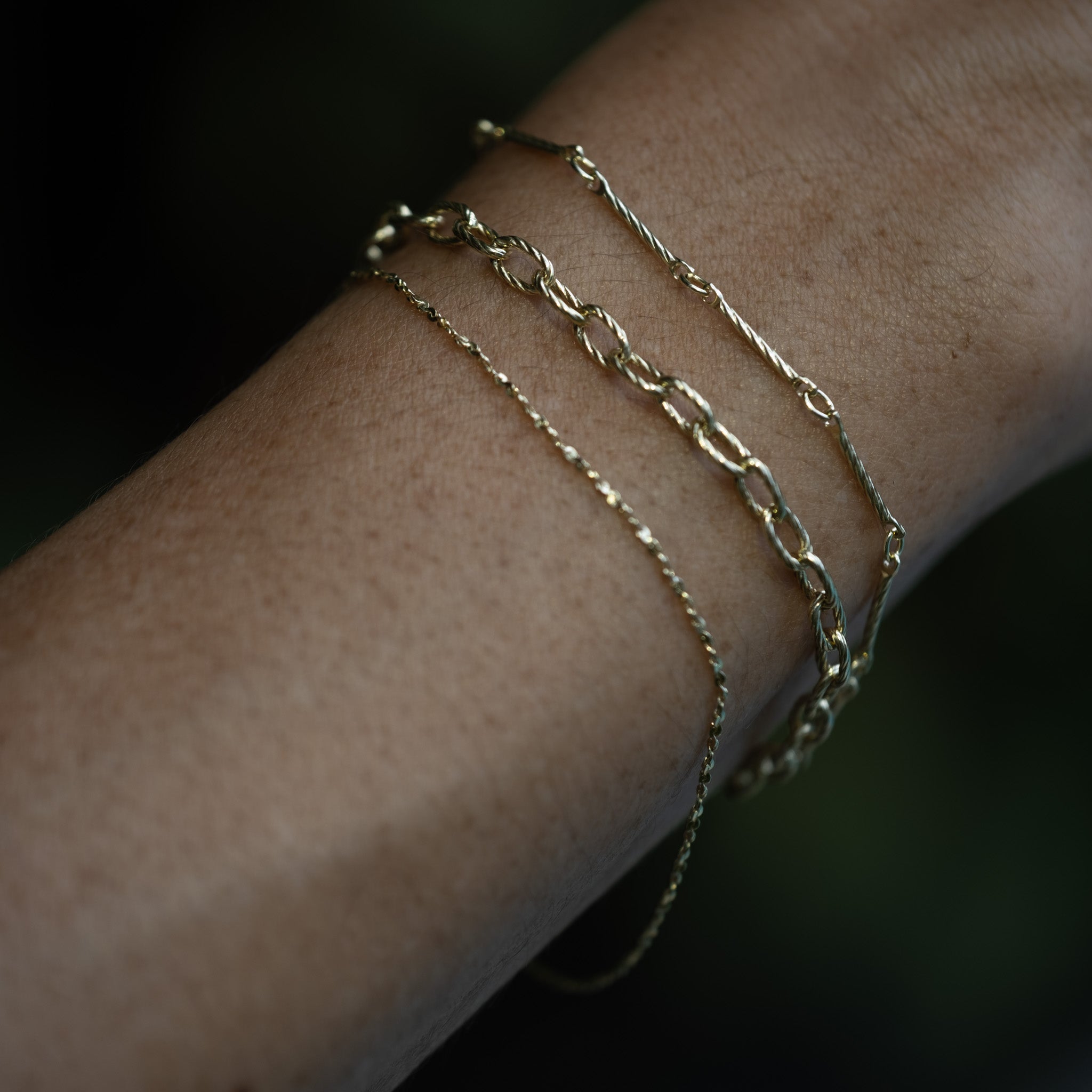 A woman's arm with solid 9k yellow gold Aiden Jae Bracelets on it.