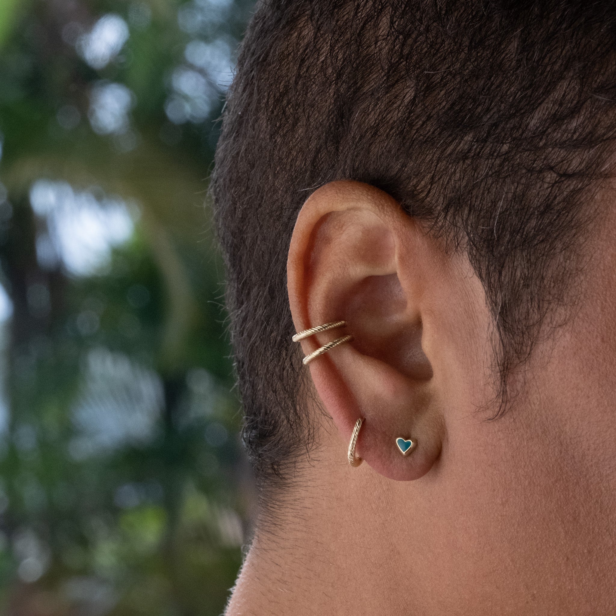 a close up of a person with an Aiden Jae Banyan Huggie ear piercing.