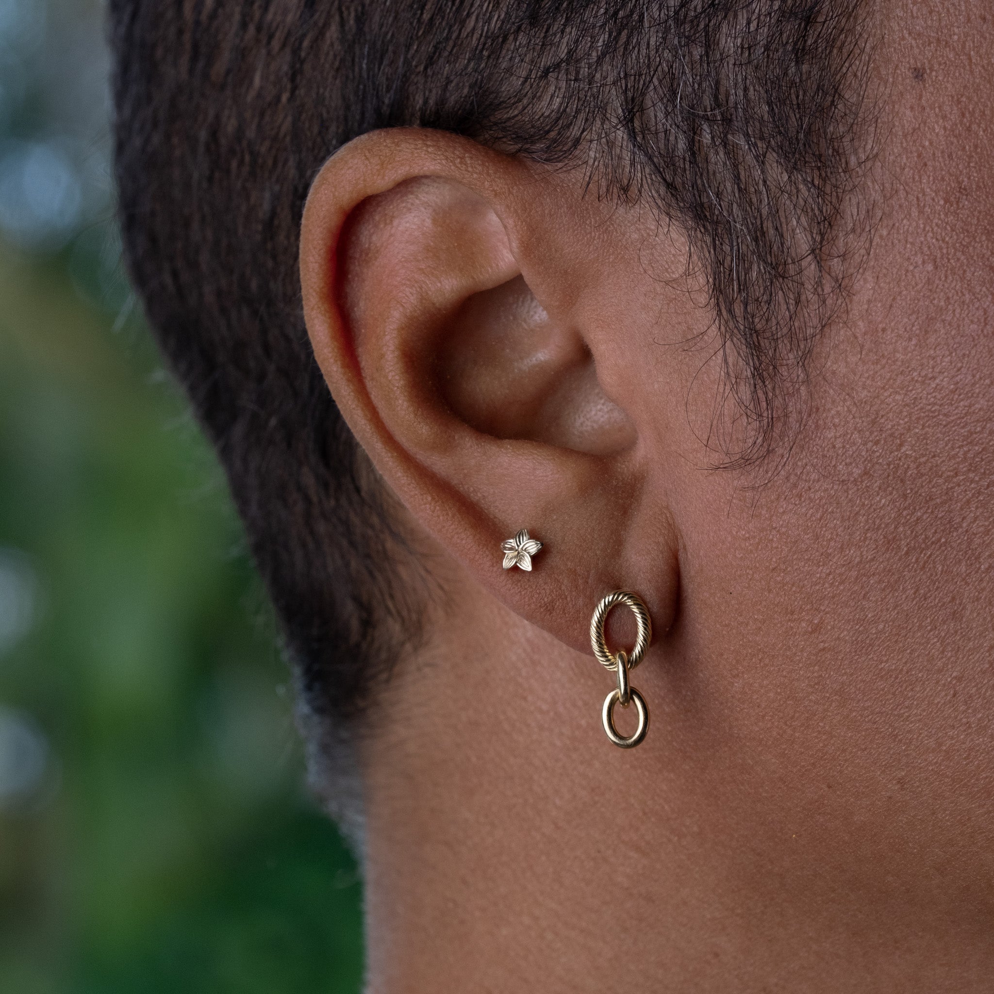 A close up of a person wearing a pair of Aiden Jae Banyan Link Earrings.