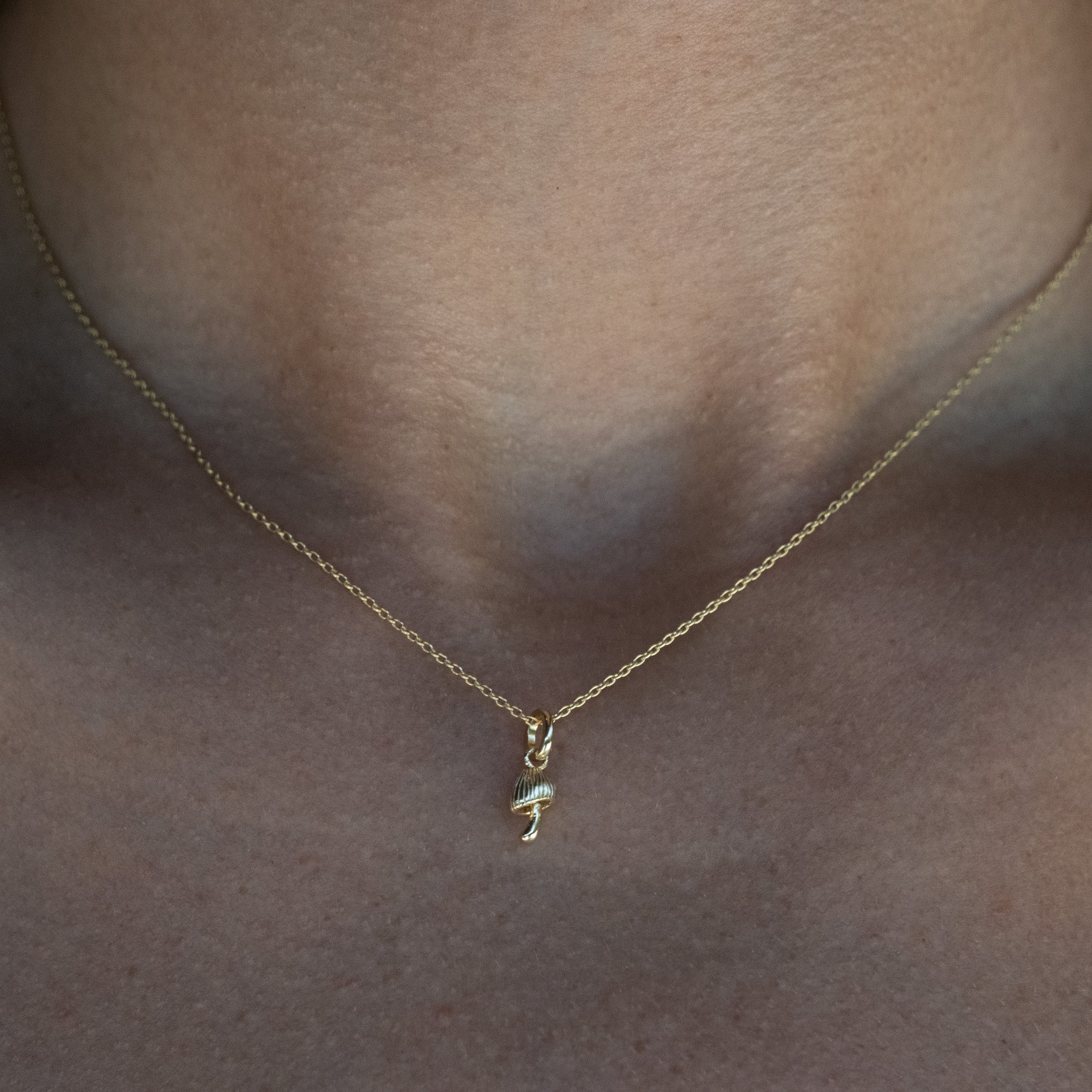 A close up of a person wearing an Aiden Jae Mini Mushroom Charm necklace.