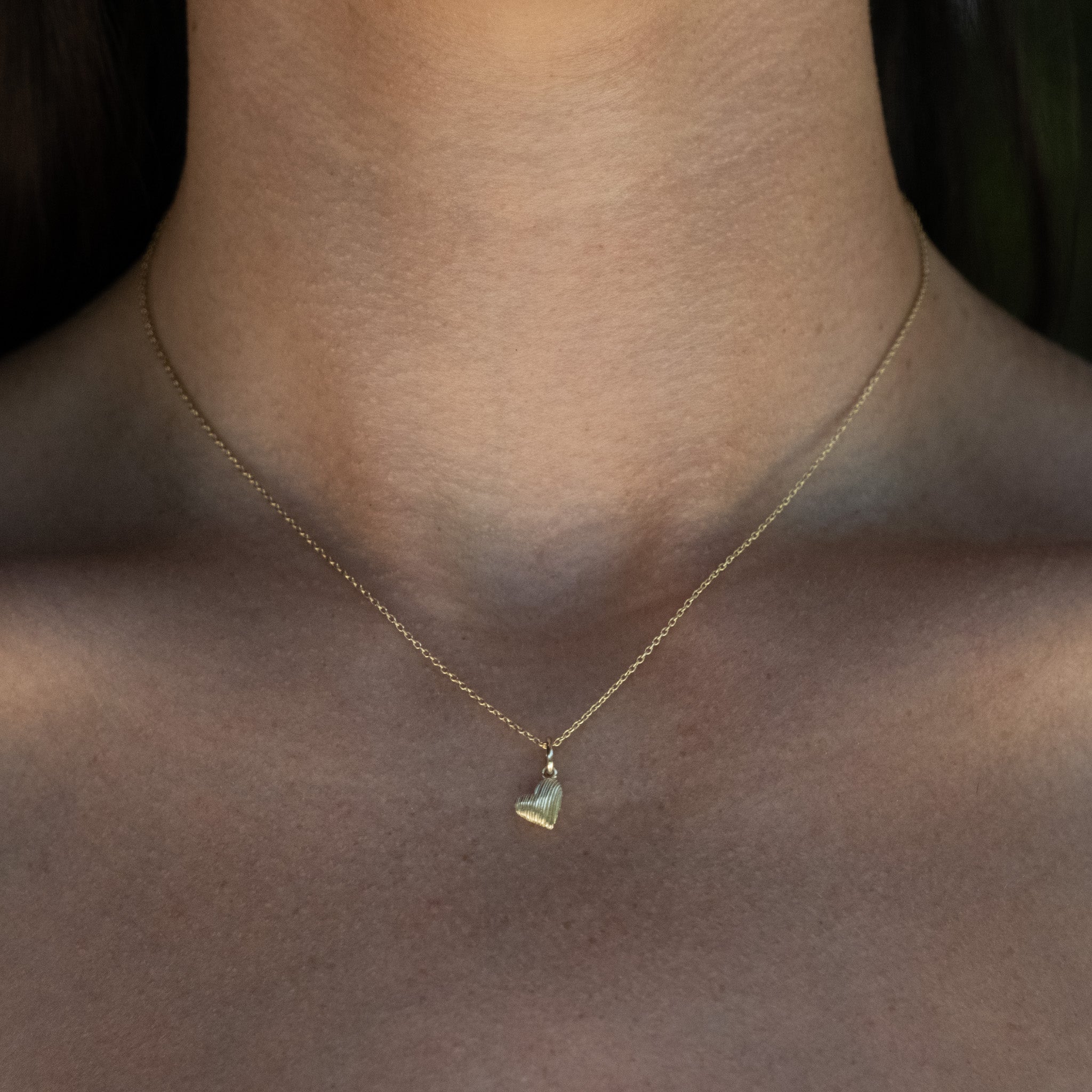 A woman wearing an Aiden Jae Mini Reversible Heart Charm Necklace.