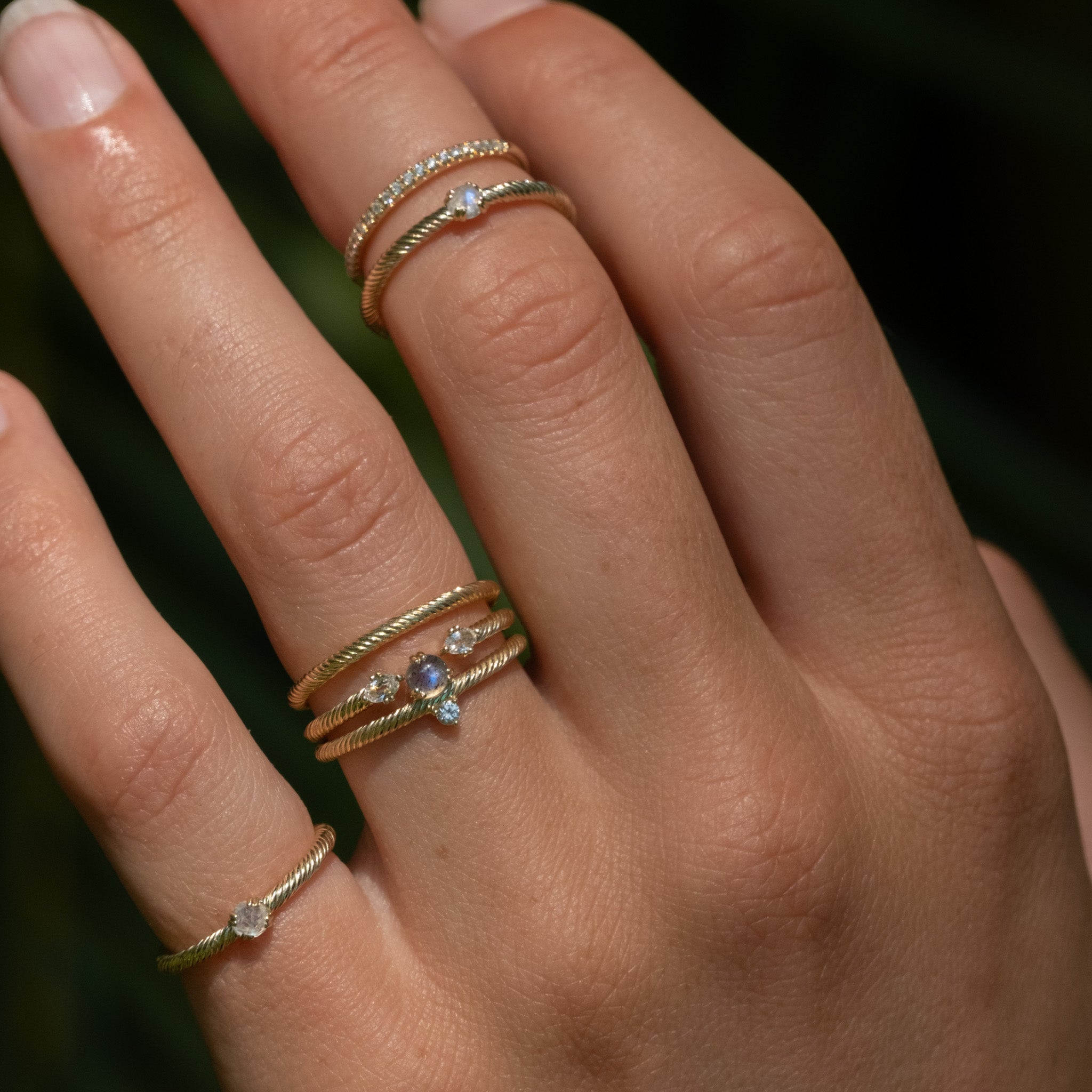 A woman's hand with three different Aiden Jae Starlight Rings on it.