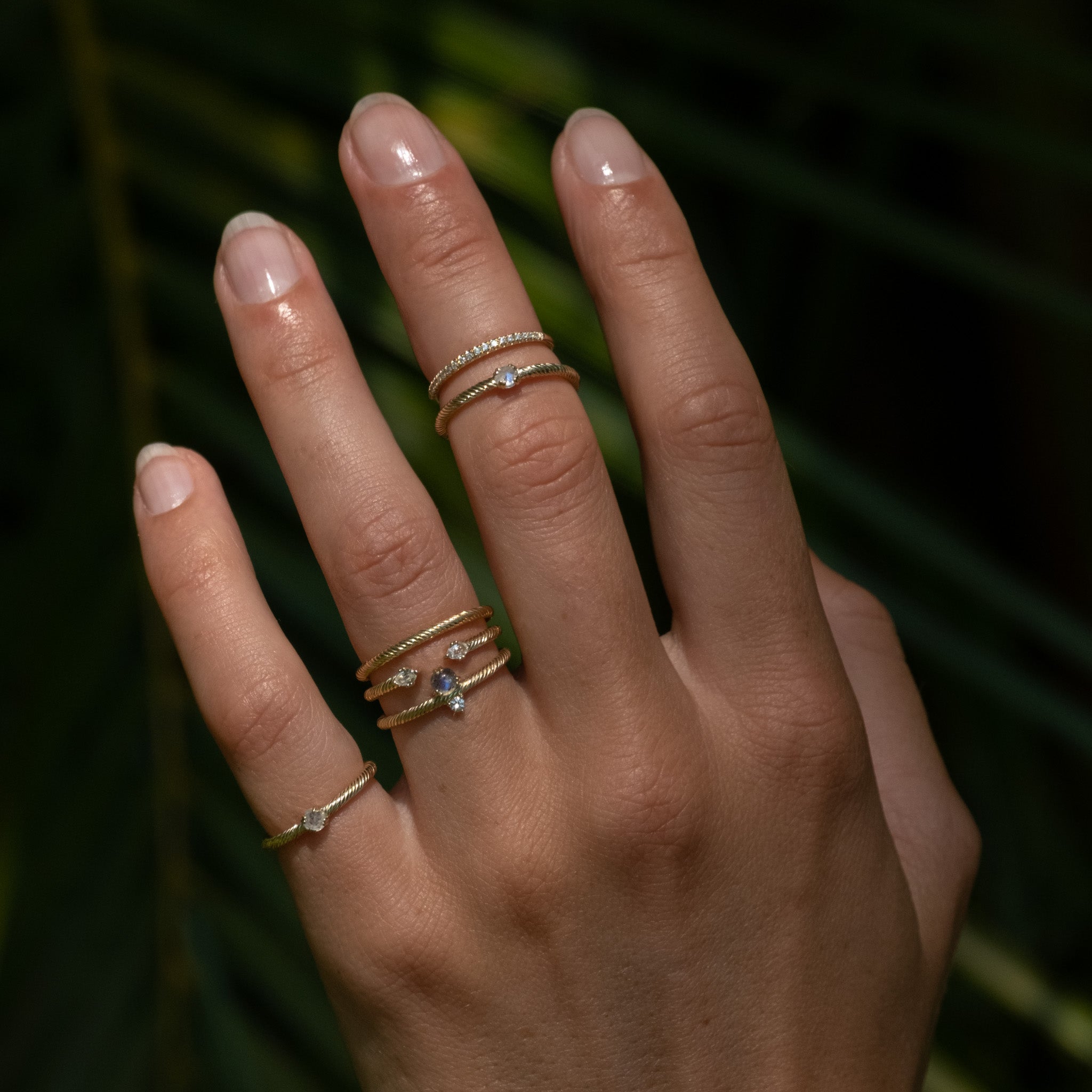 A woman's hand with three Aiden Jae Moonlight Rings on it.