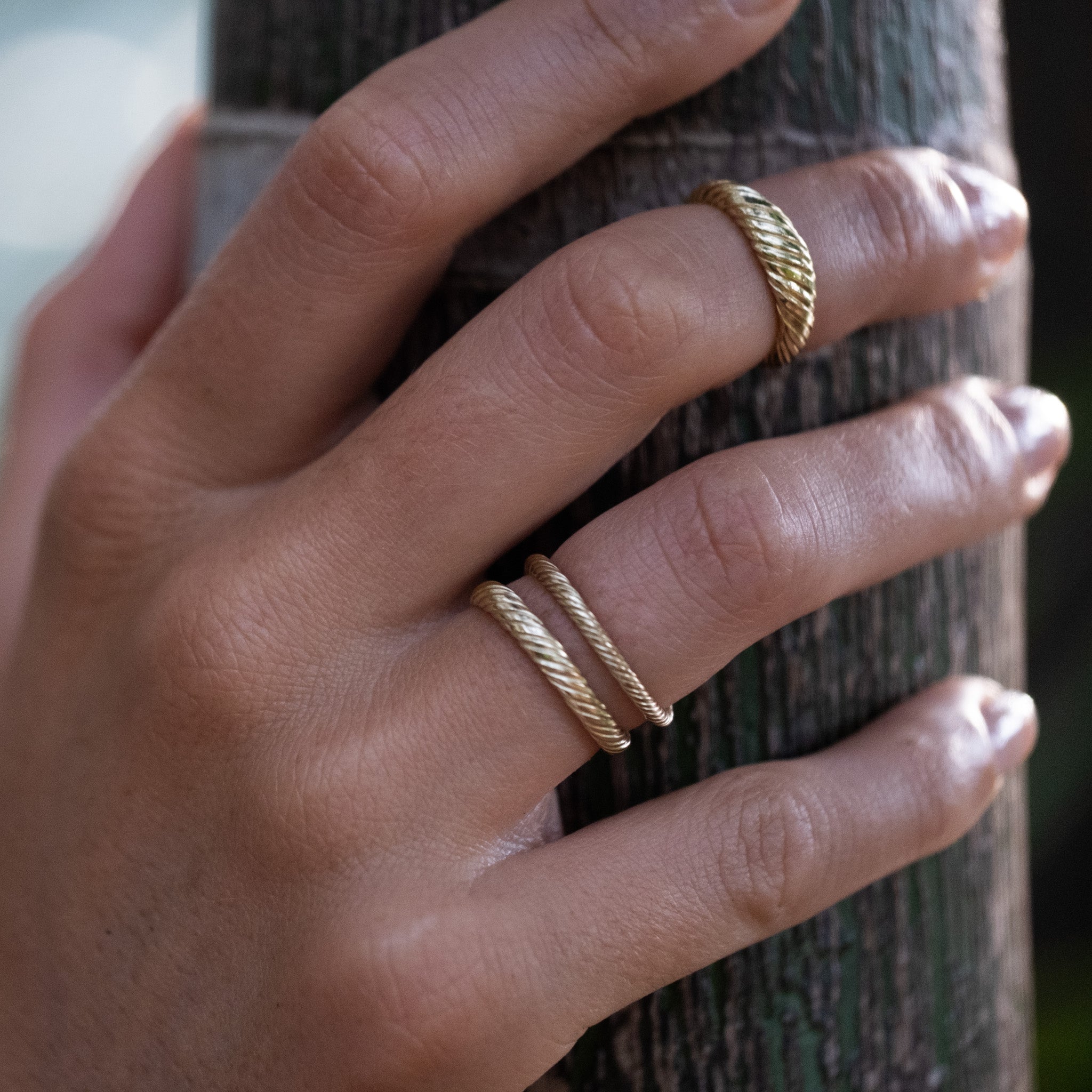 A woman's hand with two Aiden Jae Banyan Dome Rings on it.