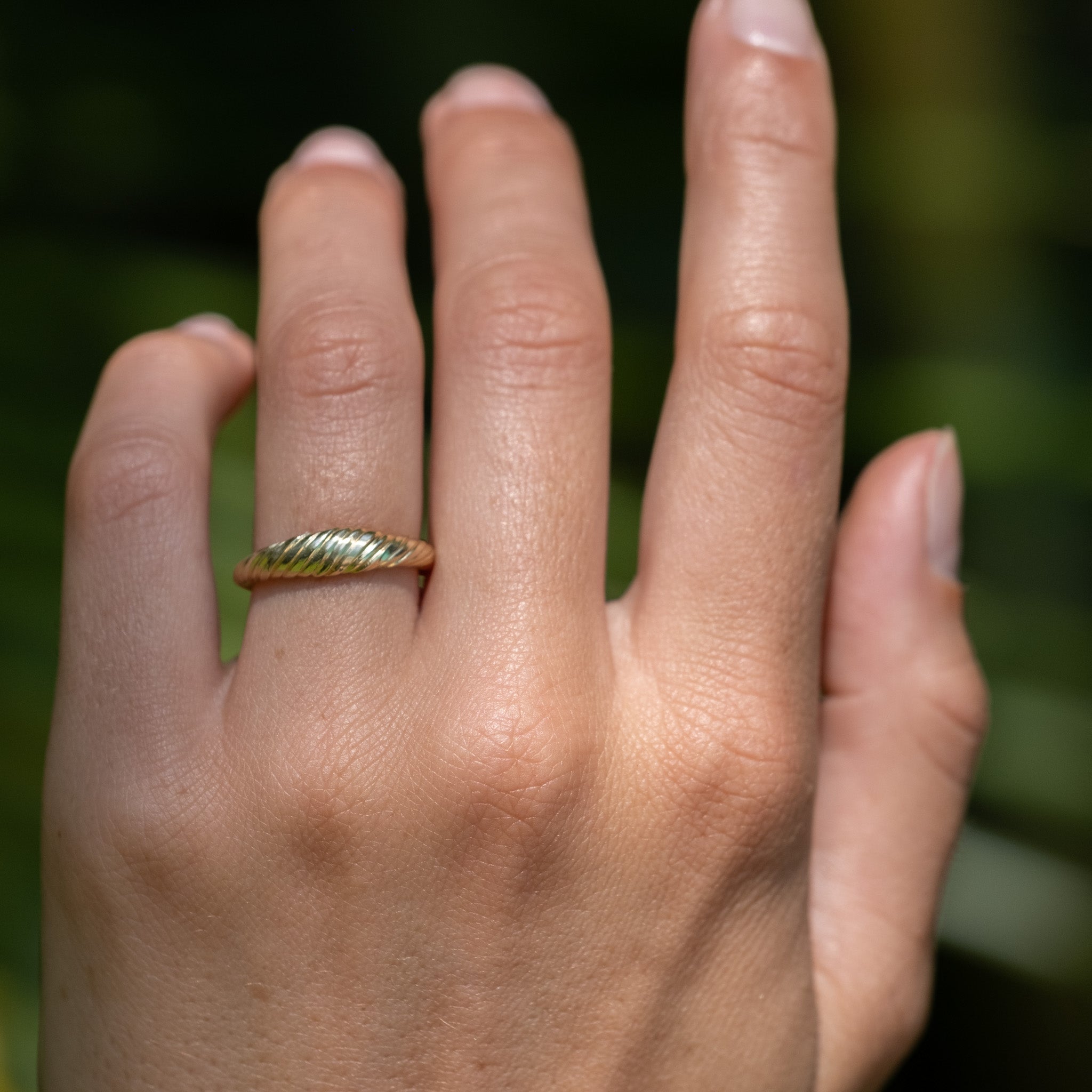 Solid gold dome ring with twisted texture and minimalist design, worn on hand.