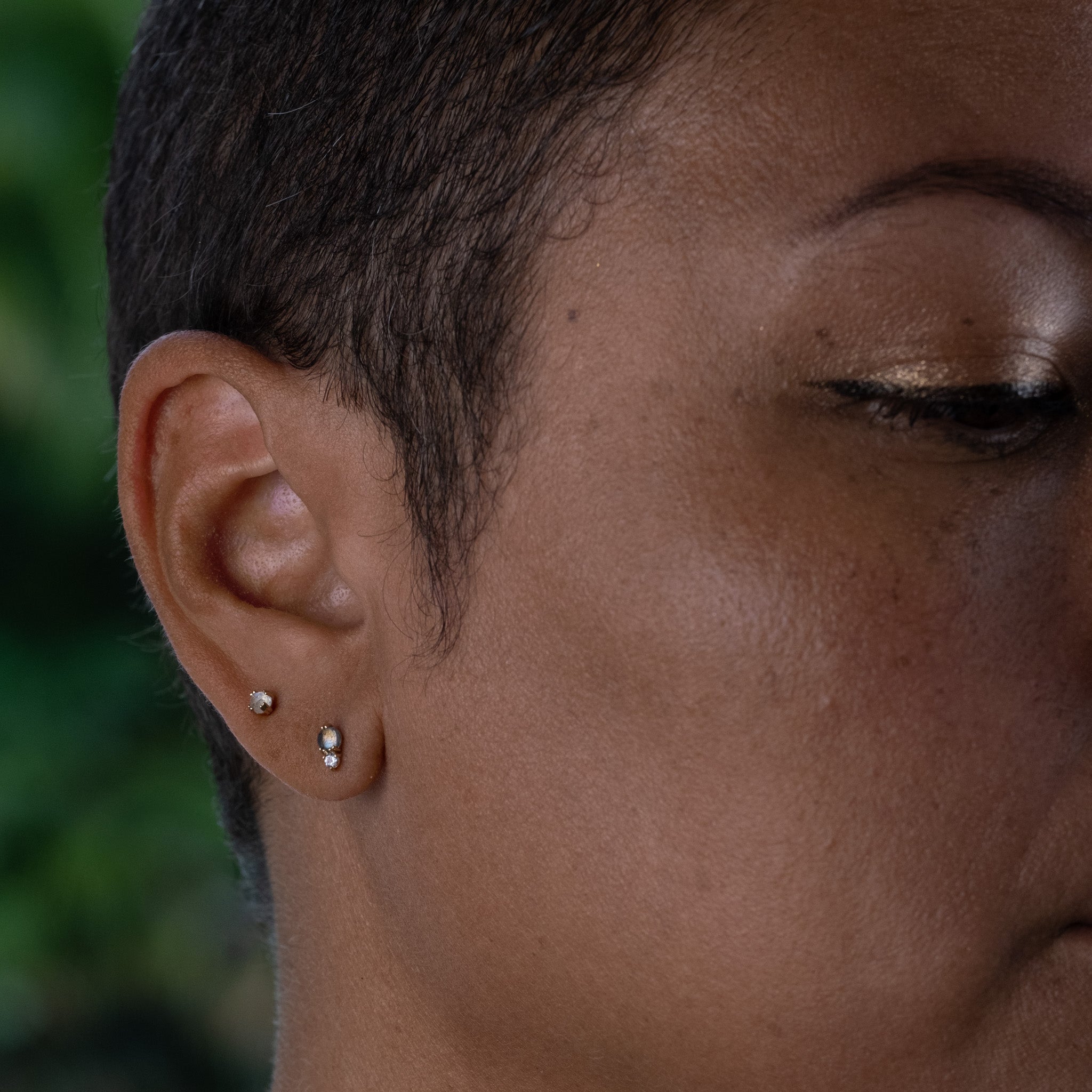 Solid gold stud earring stack with labradorite, white sapphire, and rainbow moonstone in minimalist designs, worn on ear.