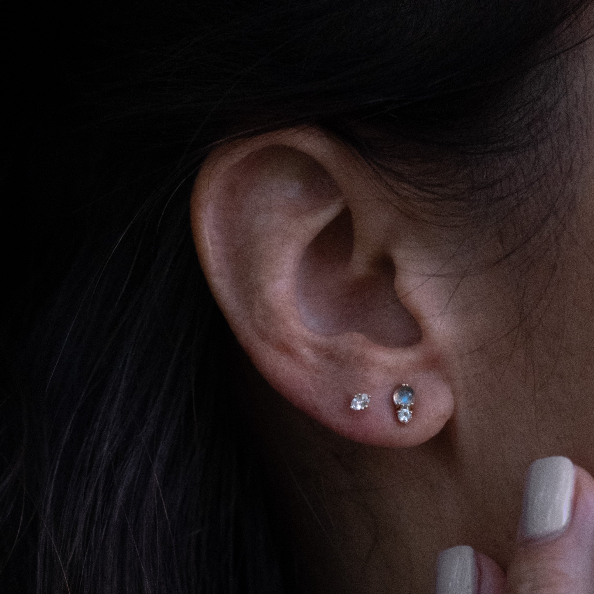 Solid gold stud earring stack with labradorite and white sapphire gemstones in minimalist designs, worn on ear.