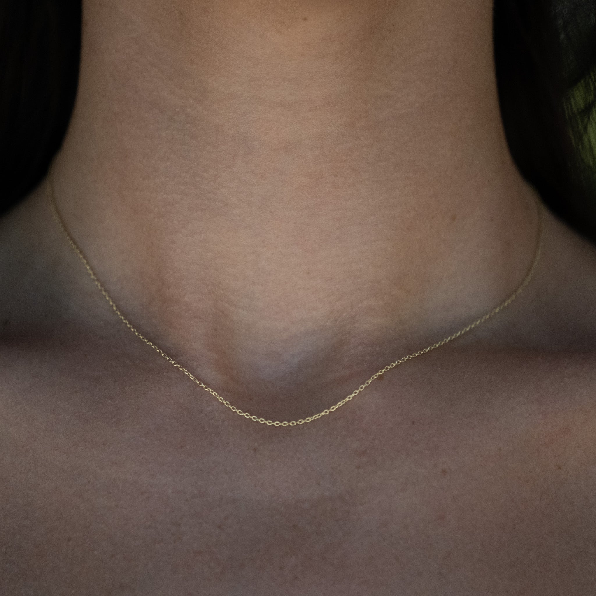 Solid gold cable chain pendant necklace, worn on neck.