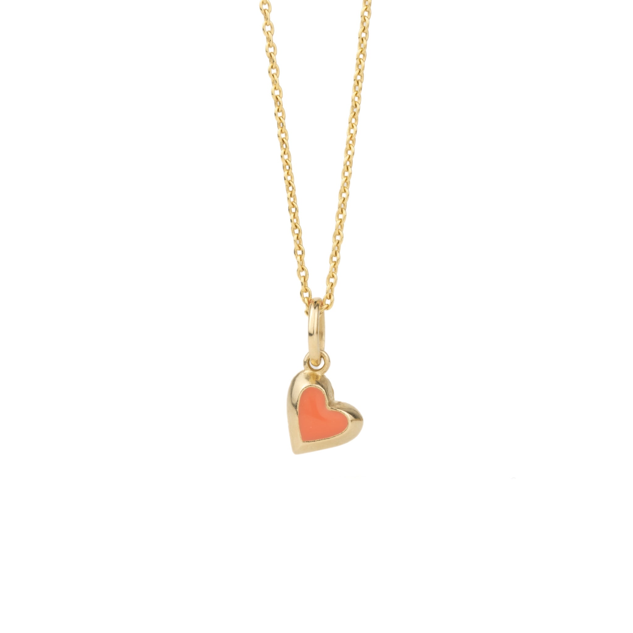 Solid gold tiny heart charm pendant with coral enamel on cable chain, in a minimalist asymmetrical design, on white background.