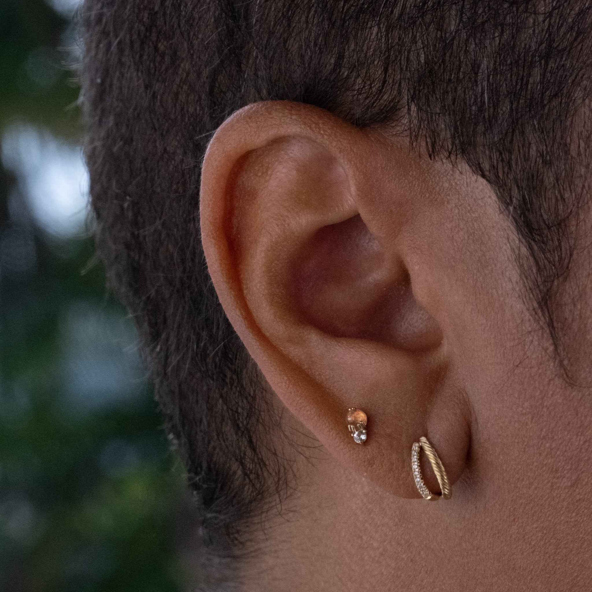 Solid gold stud and double hoop earring stack with sunstone, white sapphire, and diamonds in minimalist designs, worn on ear.