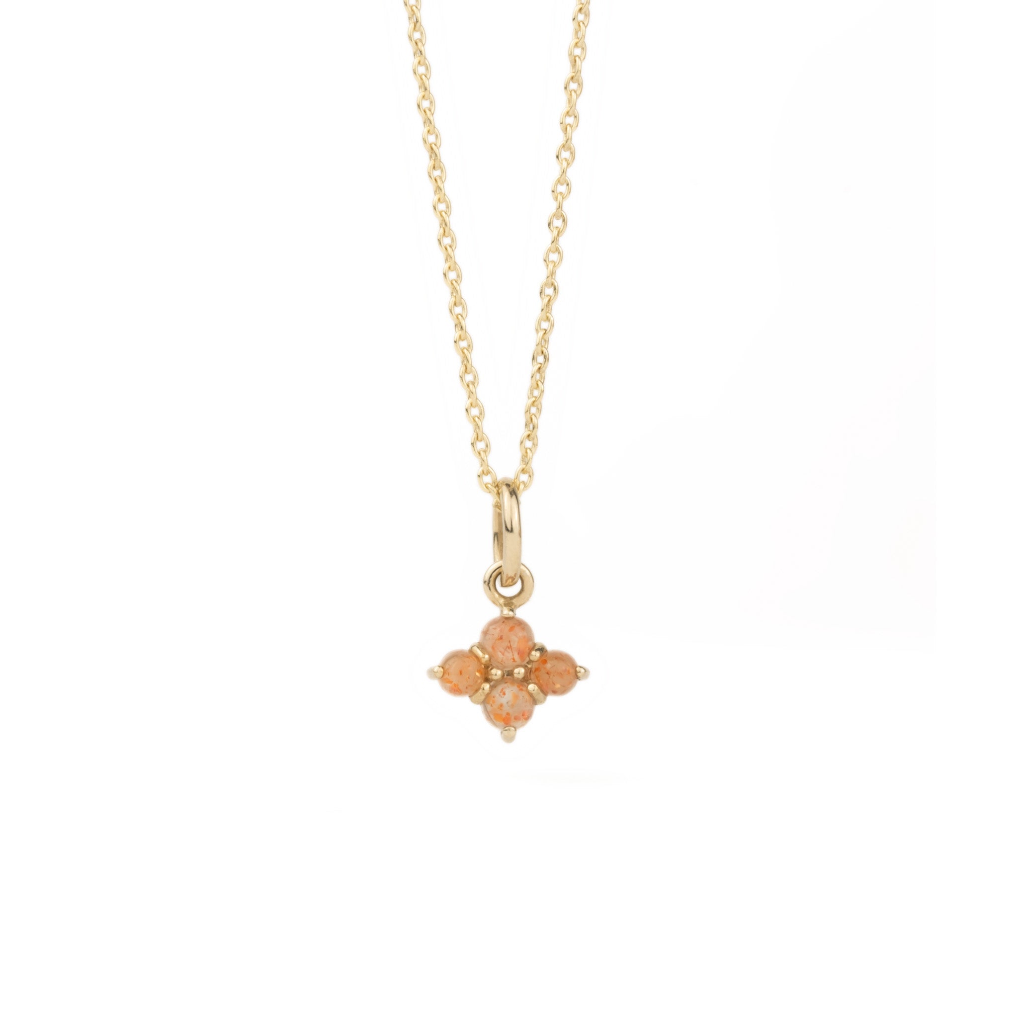 Solid gold small charm pendant with cabochon sunstones, in a minimalist design, hanging on cable chain on white background.